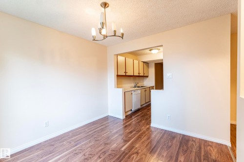 Wood-finish flooring with a bronze-tone chandelier - #4 3221 119 St Nw, Edmonton, AB 
