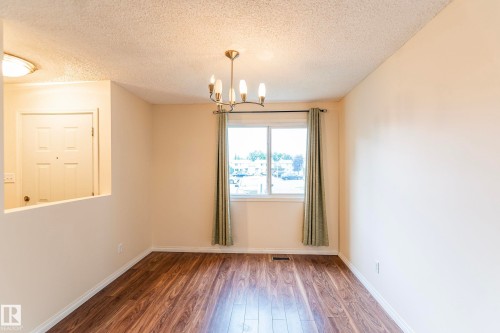 Hardwood-style flooring, light-toned walls, and a multi-bulb chandelier - #4 3221 119 St Nw, Edmonton, AB 