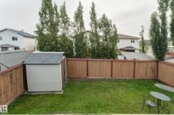 Fenced backyard featuring a manicured lawn and two storage sheds - 