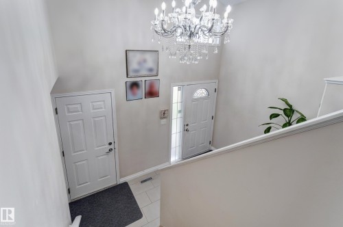 Entryway featuring a decorative chandelier, white panel doors, and tile flooring - 3519 22 Street Nw, Edmonton, AB 