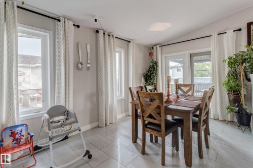 Light-toned wall paint with a vaulted ceiling, multiple large windows, and an exterior glass-paneled door - 3519 22 Street Nw, Edmonton, AB 