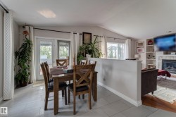 Dining area with light gray tile flooring, vaulted ceiling, and double glass-paned doors - 