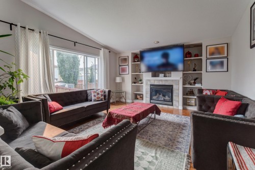 Fireplace with mantel, built-in shelving, sliding glass door, recessed lighting, and wood-finish flooring - 3519 22 Street Nw, Edmonton, AB 