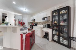 Kitchen featuring white cabinetry, light-toned countertops, mosaic tile backsplash, built-in microwave, and stainless steel refrigerator - 