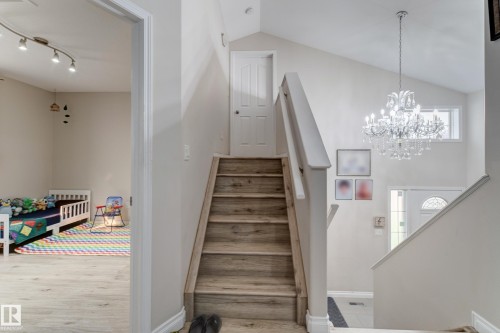 Vaulted ceiling with an elegant chandelier, wood-finish flooring, and white interior doors - 3519 22 Street Nw, Edmonton, AB 