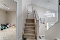 Vaulted ceiling with an elegant chandelier, wood-finish flooring, and white interior doors - 