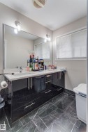 Double vanity with a white countertop and undermount sinks, set upon a black cabinet with metal pull hardware - 
