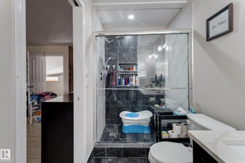 Glass-enclosed shower with dark-toned, veined tile, complemented by a white quartz countertop vanity with an integrated sink - 3519 22 Street Nw, Edmonton, AB 