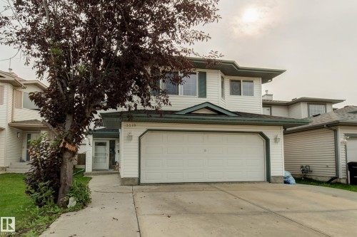 Two-story residence featuring light-colored siding, a two-car garage, and a concrete driveway - 3519 22 Street Nw, Edmonton, AB 