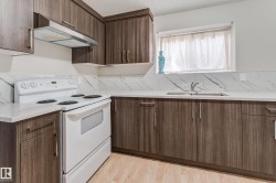 Wood-finish cabinetry, light-toned countertops, white range, stainless steel range hood, and a stainless steel sink - 