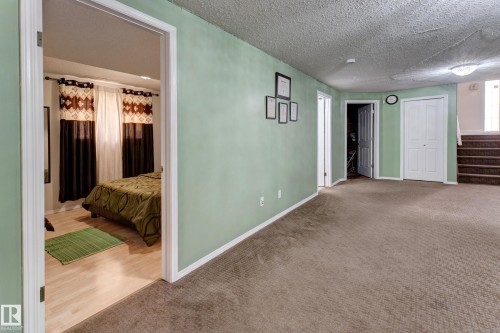 Carpeted flooring, light green wall finishes, white trim, and a built-in closet with bi-fold doors - 3519 22 Street Nw, Edmonton, AB 