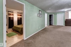Carpeted flooring, light green wall finishes, white trim, and a built-in closet with bi-fold doors - 