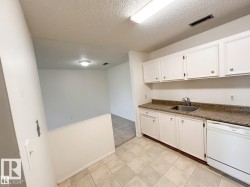 Kitchenette featuring white cabinetry, a stainless steel sink, granite-finish countertops, and a white dishwasher - 