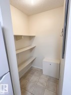 Integrated storage area featuring multiple shelving units, tiled flooring, and a compact built-in cabinet - 