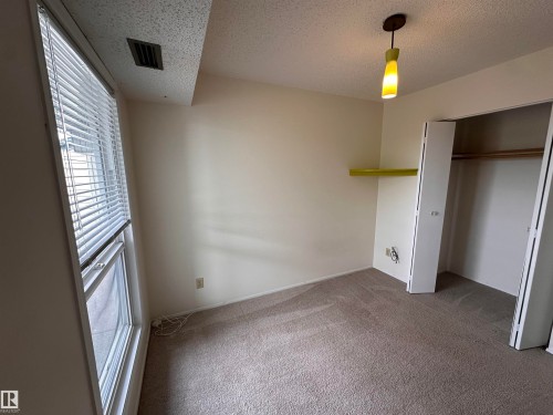 Wall-to-wall carpeting, window with blinds, overhead light fixture, built-in wall shelf, and bi-fold closet doors - #132 2703 79 St Nw, Edmonton, AB 