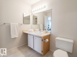 Bathroom featuring a vanity with a laminate countertop, an integrated sink, a wood-finish cabinet with white paneled doors, and a large wall-mounted mirror - 