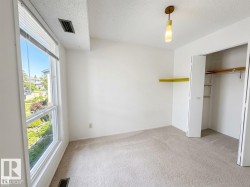 Bright room featuring a large window with blinds, a built-in closet with bi-fold doors, and a ceiling-mounted light fixture - 