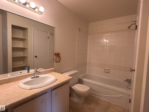 Bathroom featuring a built-in vanity with an integrated sink, a full-width mirror, overhead vanity lighting, a built-in bathtub with shower, and tile flooring - #132 2703 79 St Nw, Edmonton, AB 