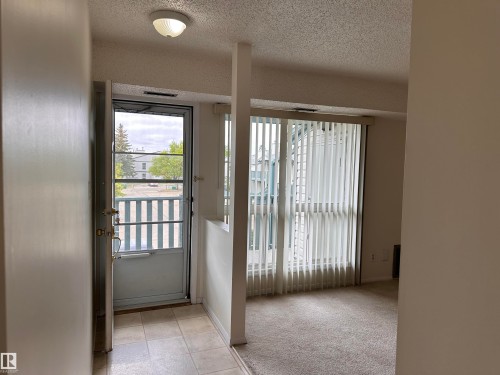 Entryway with neutral tile flooring, leading to a carpeted interior space - #132 2703 79 St Nw, Edmonton, AB 