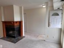 Living space with a wood-mantel fireplace featuring a brick surround and slate tile hearth - #132 2703 79 St Nw, Edmonton, AB 