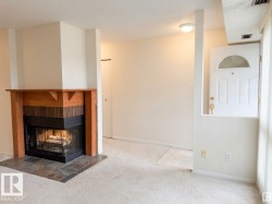 Wood-mantle fireplace with brick surround, slate tile hearth, and carpeted flooring - 