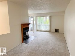 Carpeted living area featuring a fireplace with a wood mantel and tile hearth, and a large window with vertical blinds - 