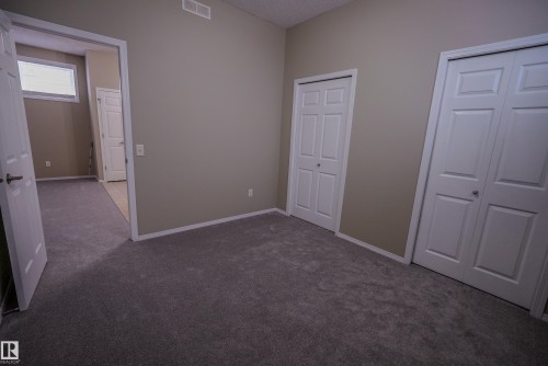 Neutral tone wall paint, grey carpet flooring, white trim, and white bi-fold closet doors - 122 142 Selkirk Place, Leduc, AB 