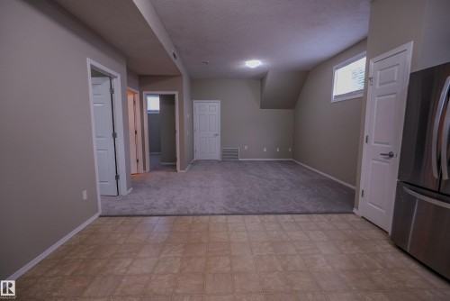 Tile flooring, plush carpeting, recessed lighting, white interior doors, and a stainless steel refrigerator - 122 142 Selkirk Place, Leduc, AB 