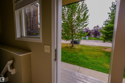 Bright interior space with glass door entry opening to expansive lawn and mature landscaping - 122 142 Selkirk Place, Leduc, AB 