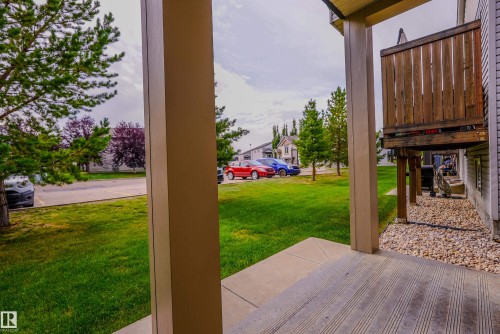 Covered patio with textured concrete flooring, overlooking a green lawn with mature trees - 122 142 Selkirk Place, Leduc, AB 