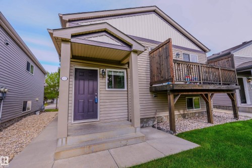 Modern townhome featuring a covered front entry with gabled roofline, purple composite door, and large front-facing window - 122 142 Selkirk Place, Leduc, AB 