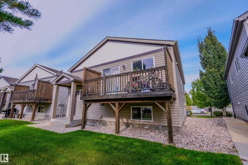 Outdoor decking with wood railings, sliding glass door access, and a ground-level window - 122 142 Selkirk Place, Leduc, AB 