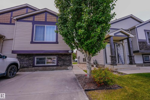 Siding exterior with decorative stone accents, a covered entry porch, concrete steps, and a paved driveway - 122 142 Selkirk Place, Leduc, AB 