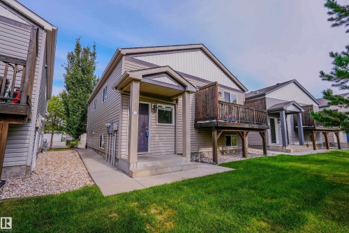 Exterior featuring a covered entry, light-colored siding, and a wooden deck with privacy screening - 122 142 Selkirk Place, Leduc, AB 