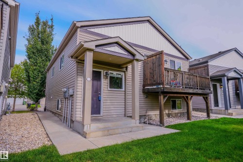 Two-story residence featuring light-colored siding, a covered front entry, and an elevated wood deck - 122 142 Selkirk Place, Leduc, AB 