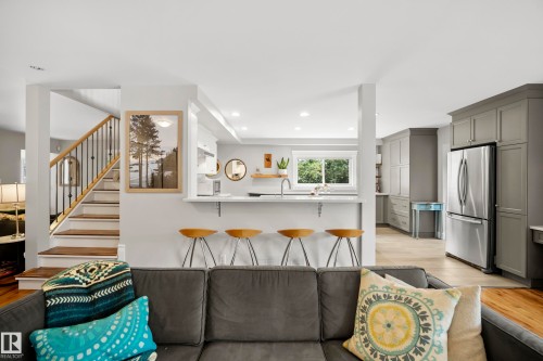 Open-concept living area featuring a kitchen with stainless steel appliances, light-toned cabinetry, and a breakfast bar - 11006 64 Avenue Nw, Edmonton, AB 