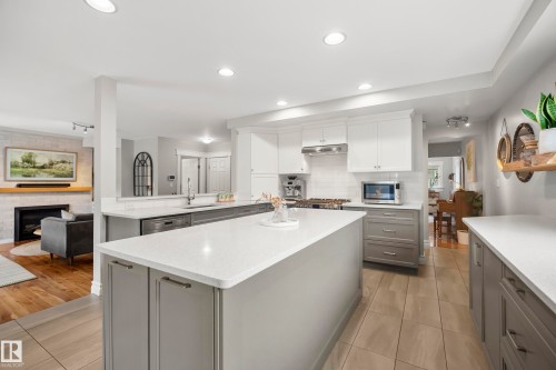 Kitchen featuring a central island with a light-toned countertop, white upper cabinetry, gray lower cabinetry, and recessed lighting - 11006 64 Avenue Nw, Edmonton, AB 