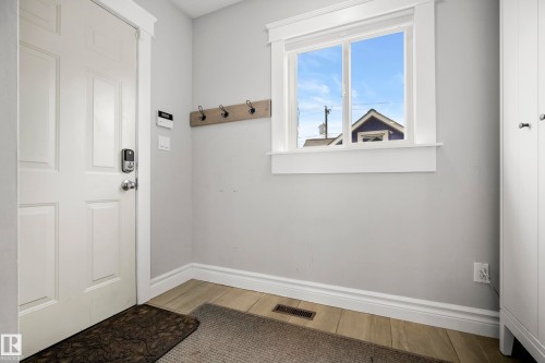 Entryway featuring a paneled door, wood-finish flooring, and a built-in coat rack - 11006 64 Avenue Nw, Edmonton, AB 