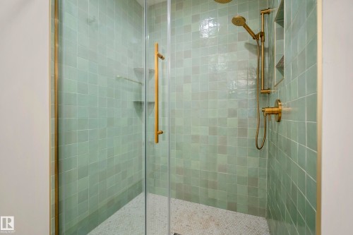 Glass-enclosed shower with square green wall tiles, gold-finish fixtures, and a recessed niche - 11006 64 Avenue Nw, Edmonton, AB 