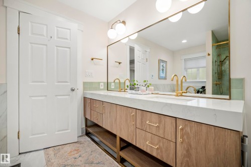Dual vanity with wood-finish cabinetry, integrated sinks, white countertop, and brass fixtures - 11006 64 Avenue Nw, Edmonton, AB 