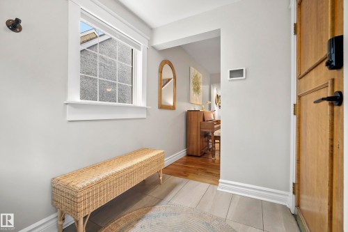 Entryway featuring a solid wood door, light-toned tile flooring, and a window with white trim - 11006 64 Avenue Nw, Edmonton, AB 