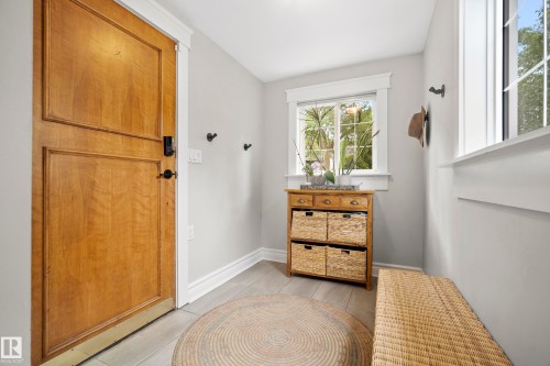 Wood-finish entry door with black hardware, light gray walls, and light-toned flooring - 11006 64 Avenue Nw, Edmonton, AB 