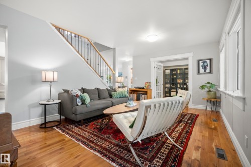 Hardwood flooring, white trim, staircase with wood handrail and black balusters, recessed lighting, and French doors - 11006 64 Avenue Nw, Edmonton, AB 