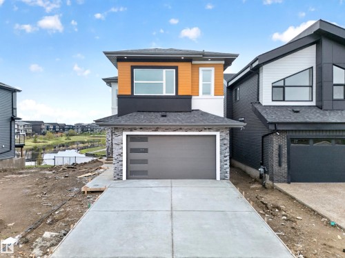 Contemporary exterior with mixed material siding, a prominent two-car garage, and a concrete driveway - 8737 Mayday Lane Sw, Edmonton, AB 