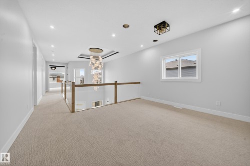Expansive carpeted landing with a contemporary chandelier and recessed lighting - 8737 Mayday Lane Sw, Edmonton, AB 