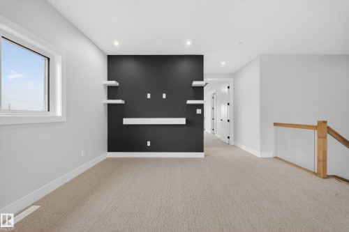 Recessed lighting, wall-mounted shelving, neutral carpet flooring, and a natural wood staircase with glass panels - 8737 Mayday Lane Sw, Edmonton, AB 