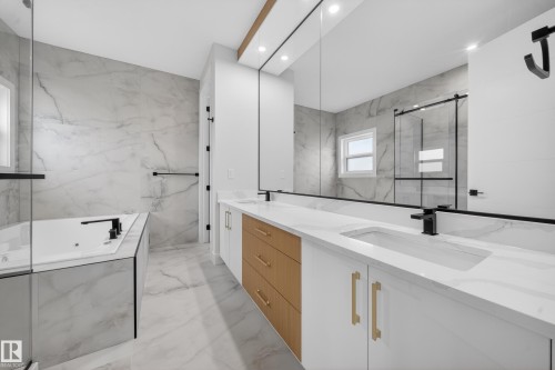 Dual vanity with integrated sinks, white countertops, wood-finish and white cabinetry, a built-in soaking tub, and a glass-enclosed shower - 8737 Mayday Lane Sw, Edmonton, AB 
