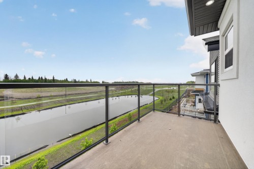 Private balcony with glass railing, concrete flooring, exterior recessed lighting, and a serene water feature - 8737 Mayday Lane Sw, Edmonton, AB 