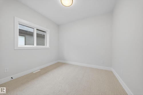 Bright room with neutral wall paint, light-colored carpet, white trim, and a window with white framing - 8737 Mayday Lane Sw, Edmonton, AB 