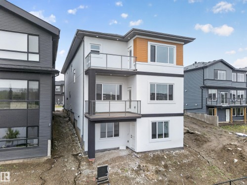 Modern three-story exterior featuring white stucco and wood-look paneling - 8737 Mayday Lane Sw, Edmonton, AB 
